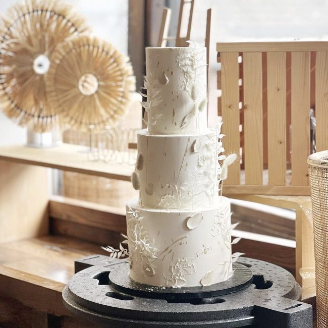 Eine dreistöckige Hochzeitstorte steht auf einer Tortenplatte.