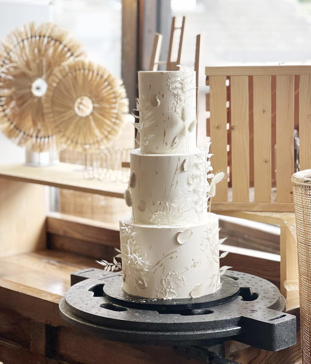 Eine dreistöckige Hochzeitstorte steht auf einer Tortenplatte.
