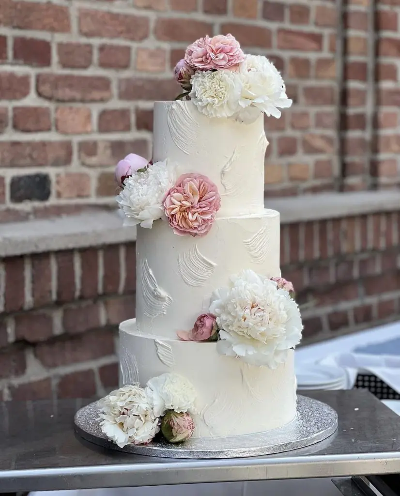 Dreistöckige Torte für Hochzeit mit Blumen dekoriert.